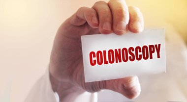 Doktor metnin olduğu bir kart tutuyor. Kolonoskopi. Seçici odaklanma. Tıbbi konsept.