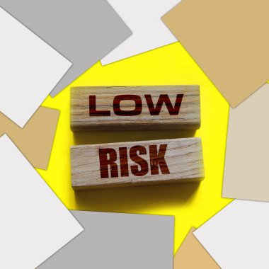 Düşük riskli kelimeler sarı üzerine tahta bloklar. İş yatırımları konsepti riske atıyor