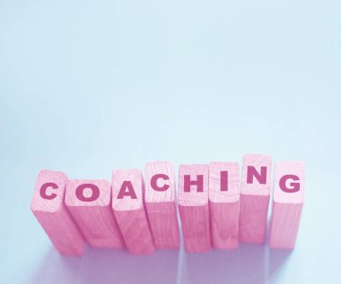 Coaching word on wooden blocks on aqua blue background. Personal and business achievements concept. clipart