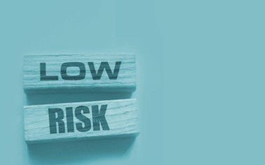 Düşük riskli kelimeler sarı üzerine tahta bloklar. İş yatırımları konsepti riske atıyor.