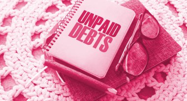 Unpaid debts words on page of copybook, glasses, pen. Financial obligations concept. Refinancing debts business loan concept. clipart