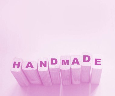 Tahta bloklar ve açık mavi arka planda el yapımı bir kelime. Hobi el yapımı mal konsepti, küçük perakende iş kurma kavramı.