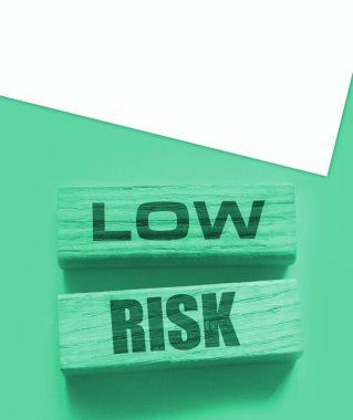 Düşük riskli kelimeler sarı üzerine tahta bloklar. İş yatırımları konsepti riske atıyor.