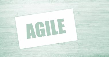 Kağıt kartvizitte AGILE yazılı, ahşap arka planda yakın plan. İş Konsepti