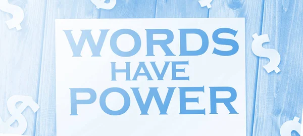 Words have power text on page and paper dollar signs around on wooden table. Copywritting storytelling marketing concept.