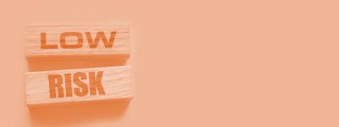 Düşük riskli kelimeler sarı üzerine tahta bloklar. İş yatırımları konsepti riske atıyor.