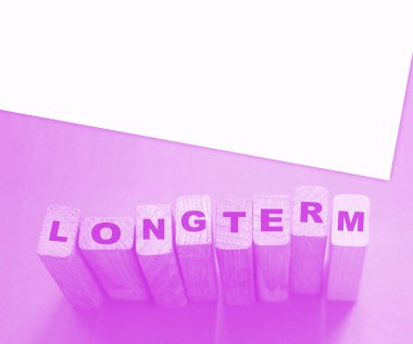 Mor arka planda tahta küplerle ilgili uzun vadeli bir kelime. Güvenilir iş uzun vadeli ilişki kavramı. 