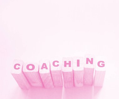 Coaching word on wooden blocks on aqua pink background. Personal and business achievements concept.   clipart