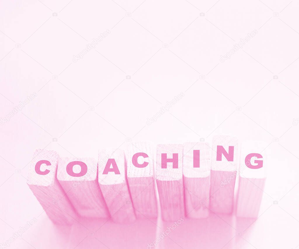Coaching word on wooden blocks on aqua pink background. Personal and business achievements concept.  