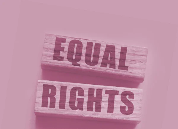 Equal rights words on wooden blocks on yellow background. Gender equality concept.