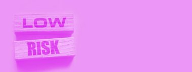 Düşük riskli kelimeler sarı üzerine tahta bloklar. İş yatırımları konsepti riske atıyor.