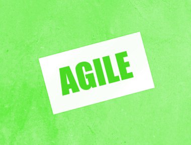 Kağıt kartvizitte AGILE yazılı, ahşap arka planda yakın plan. İş Konsepti