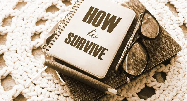 How to survive words on cover of copybook, glasses and pen. Surcvival concept. Crisis management business concept. Coronavirus prevention concept.