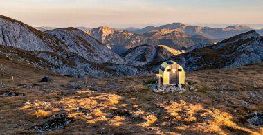 Akşam ışığında Schiestlhaus dağ kulübesi yakınlarında yeşil çadır ve Fleischer-Biwak manzarası Hochschwab dağının tepesinde, güneşli hava, gün batımı, mavi gökyüzü. Dağ sırasındaki sonbahar titreşimleri Hochschwab, Styria, Avusturya Alpleri, Avusturya, Avrupa.