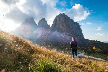 Arka planda genç bir kadın Langkofel Grup 'un dağ kulelerinde gün batımını izliyor, Grohmannspitze Dağı, Fuenffingerspitze Dağı ve Langkofel Dağı, Sella Geçidi, Dolomites, Alto Adige, İtalya