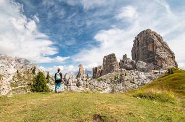 Young female hiker standing and looking at Cinque Torri view from Rifugio Scoiattoli (refuge). Dolomites, Trentino Alto Adige region, South Tyrol, Italy, Europe.