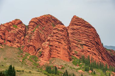 Jeti-Oguz Rocks In Kyrgyzstan. Jety-Oguz gorge Canyon, cliffs of seven bulls. Red rocks, erosion in clay, cloudy sky and steppe vegetation. Kyrgyzstan Grand Canyon, Central Asia.