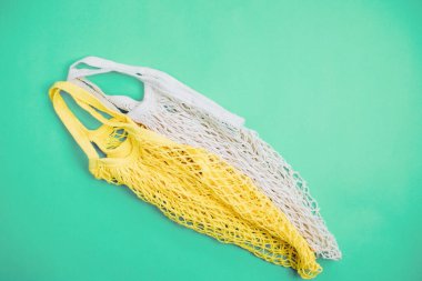 Plastiksiz sıfır atık kavramı. Mavi arka planda tekrar kullanılabilen pamuklu ağ torbası. El yapımı. Doğayla ilgilenmek..