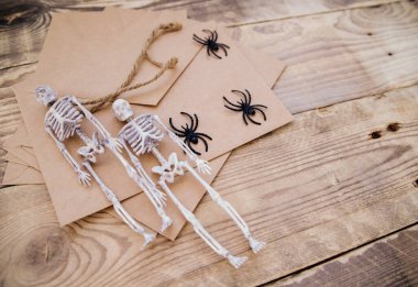 Kağıt bir zarf ve iskeletler, örümcekler, ahşap bir arka planda. Cadılar Bayramı dekoru. El yapımı tatil süslemeleri.