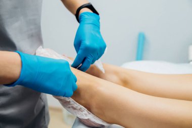 Mavi eldivenli kadın elleri müşterinin ayaklarına tek kullanımlık çoraplar giydirdi. Güzellik salonu ya da tıbbi prosedürler. Masaj veya pedikür.