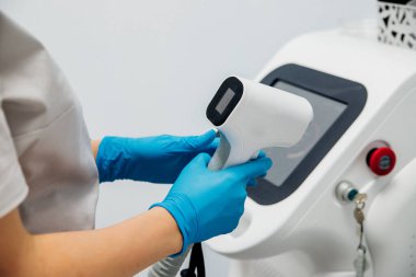 Mavi eldivenli kadın elleri bir güzellik salonunda ekipman hazırlıyor. Lazer tüy dökücü..