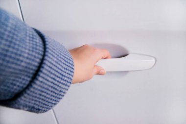 Bir kadının eli beyaz bir arabanın kapısını açar. Kilit ve alarm sistemi. Hırsızlığa karşı koruma.