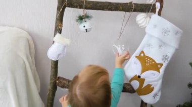 A child touches a ball hanging on a decorative staircase with his hand. Christmas decoration. A funny toy. Preparation for the holiday.