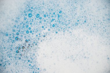Abstract background texture of white soap foam. Shampoo foam with bubbles on a blue background. Detergents and hygiene.