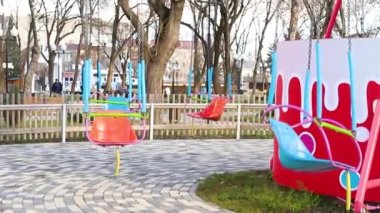 The movement of an empty children's carousel. The carousel chair moves at a low speed and stops. Entertainment in a public park. The average plan.