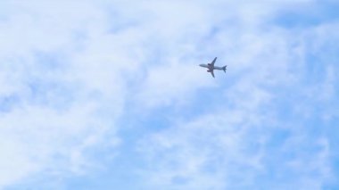A modern large airplane is flying in the sky. Beautiful blue sky and white clouds in the background. The plane flies overhead. Bright sunny day.