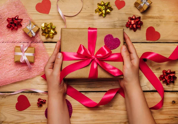 Frauenhände Halten Eine Geschenkschachtel Mit Einer Rosafarbenen Schleife Auf Einem lizenzfreie Stockfotos