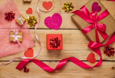 Ahşap zemin üzerinde saten kurdeleler olan hediye kutuları. Sevgililer Günü konsepti, Anneler Günü ve Doğum Günü. Kağıt kalpler ve yaylar.