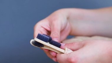 Elinde organik bambu kömür diş fırçası, gri arka plan. Çevre dostu biyolojik çözünebilir kişisel bakım ürünleri. Plastik konsept yok. Plastiksiz yaşam tarzı