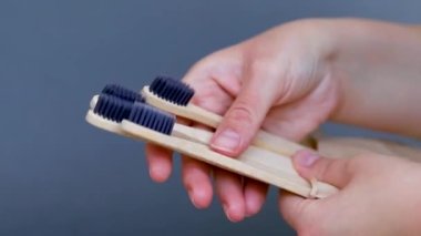Elinde organik bambu kömür diş fırçası, gri arka plan. Çevre dostu biyolojik çözünebilir kişisel bakım ürünleri. Plastik konsept yok. Plastiksiz yaşam tarzı