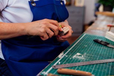 Bir kadın marangoz marangozhanede ya da geçici bir atölyede bıçakla odun keser. Toz ve talaşlar havaya dağılır. İş yeri. Ahşap oyuncaklar üretimi.