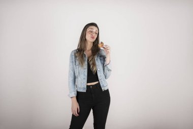 Siyah pantolon ve kot ceket giymiş sarışın bir kadının portresi, arka plandaki saf arkaplanda fotokopi çeken bir kurabiyeye bakıyor.