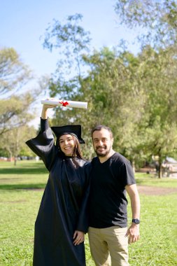 Genç kız kısa süre önce mezun oldu, kep ve cübbe giymişti, diploması ellerindeydi, üniversite kampüsünde ailesiyle kutlama yapıyordu. Çok mutlu bir ifade, başarı, yeni bir sahnenin başlangıcı.