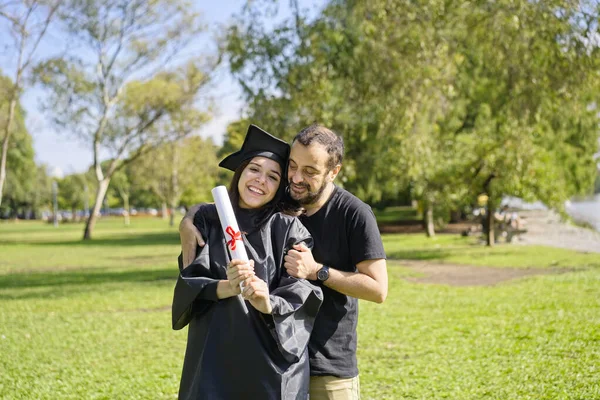 Genç kız kısa süre önce mezun oldu, kep ve cübbe giymişti, diploması ellerindeydi, üniversite kampüsünde ailesiyle kutlama yapıyordu. Çok mutlu bir ifade, başarı, yeni bir sahnenin başlangıcı.