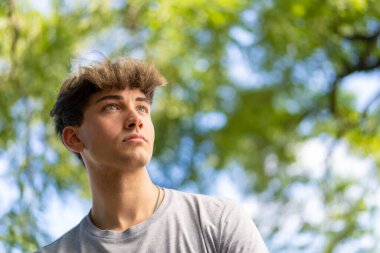 Kendine güvenen genç sarışın adam portresi, yaz ağaçları arka planı. Boşluğu kopyala