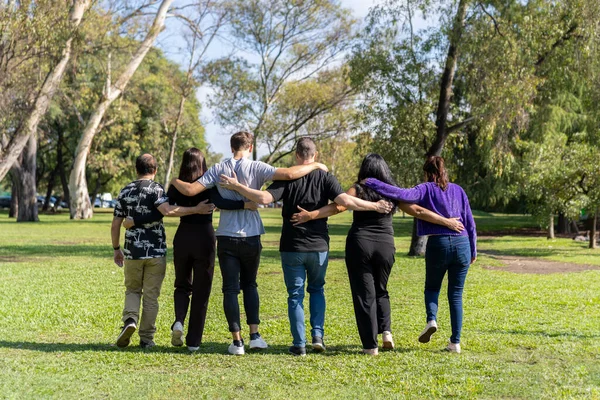 Multi ethnic family group walking arm in arm in a park. Family, group, teamwork, friendship concept