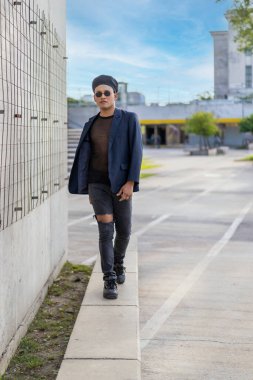 Makyajlı, moda şapkalı, sokakta podyum yürüyüşü yapan Latin eşcinsel bir erkek.