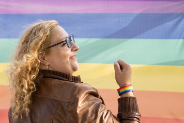 Gökkuşağı arka planında Lgbt bilekliği takan lezbiyen bir Latin kadının portresi