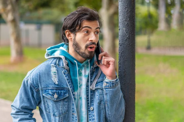 Young latin man talking on cell phone in a park