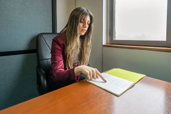 Young blonde business woman sitting in her office checking notes