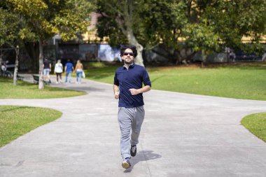 Yakışıklı, olgun, sakallı, atletik bir adamın portresi. 40 'lı yaşlarda, parkta günlük mavi tişörtlü bir adam.