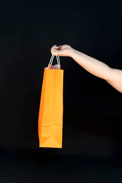 Shopping bag in the woman hands. Joy of consumption. Purchases, black friday, discounts, sale concept. Black background