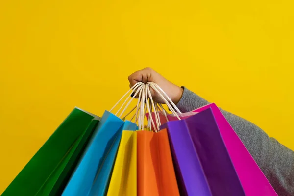 Shopping bags in the woman hands. Joy of consumption. Purchases, black friday, discounts, sale concept. Yellow background