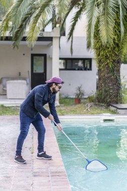 Latin adam havuz temizliği yapıyor.