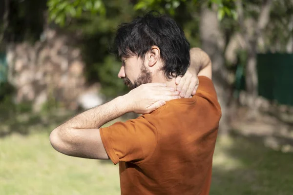 Latin adam boynuna masaj yapıyor. Boyun ağrısı olan sporcu kendisi masaj yapıyor..