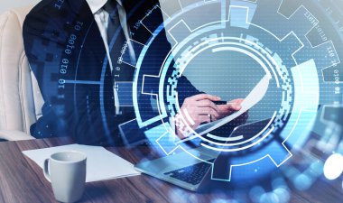 Resmi takım elbiseli bir işadamı oturuyor ve kağıda not alıyor. Bilgisayarlı ve arka planında kahve fincanı olan bir ofis. Önplandaki daire hologramıyla dijital arayüz